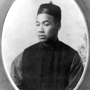 Studio portrait of Sing Lee, a Chinese-American man, in Silver Cliff (Custer County), Colorado. He wears a shirt and skullcap.