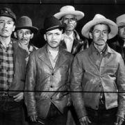 Studio portrait of Native American (Navajo) men probably in Colorado. They wear hats and jackets. One man wears a tie.