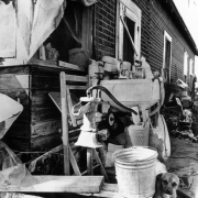 View of machinery near a migrant worker's house in Adams County, Colorado. A pail and wooden crates are nearby.