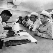 Mexican men stand at a counter in the unemployment office in Fort Lupton (Weld County), Colorado. Mexican American men fill-out forms on the other side of the counter.