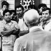 Mexican and Hispanic American men and women sit and stand at a meeting with the director of a Fort Lupton migrant worker camp in Fort Lupton (Weld County), Colorado.