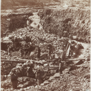 View of a hydraulic mining operation at Chinese Gulch, in (probably) Colorado; shows men working, eroded ground, sluices, and wheelbarrows.