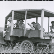 Men and women farm workers sit in the cab and back of a truck and eat lunch in a field at the Hightower Ranch near Keota in Weld County, Colorado. The truck has a homemade wooden frame and roof with a mattress in the back. The truck license place reads: "78-588 Colo. 1923." A sign on the cab reads: "Farm Vehicle Keota Colo."