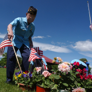 Harry Nakagawa  puts  a flag on a grave site at Fairmount Cemetery