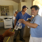 Sister Molly Munoz, right, hands bottles of water to migrant workers during their lunch break last week outside of Broomfield. The men had been working in the fields in 90-degree-plus temperatures.