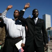 Abdirah Man, cq, from left, who hails from Ethiopia, Omar Addow, cq, from Somalia, and Augustino Majok, cq, from Sudan, raise their hands as they are sworn in as United States Citizens in Civic Center Park's Greek Amphitheater in Denver, Colo., on Tuesday