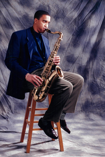 Javon Anthony Jackson playing saxophone on a stool