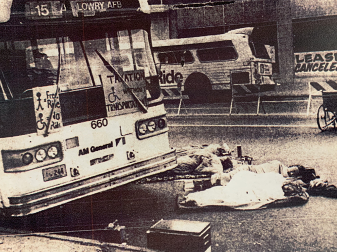 People lay in the street in front of a bus as a protest