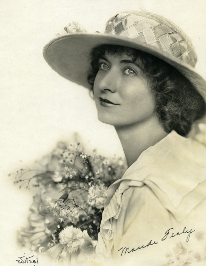 Maude as a young girl, wearing a white hat and holding baby breath flowers