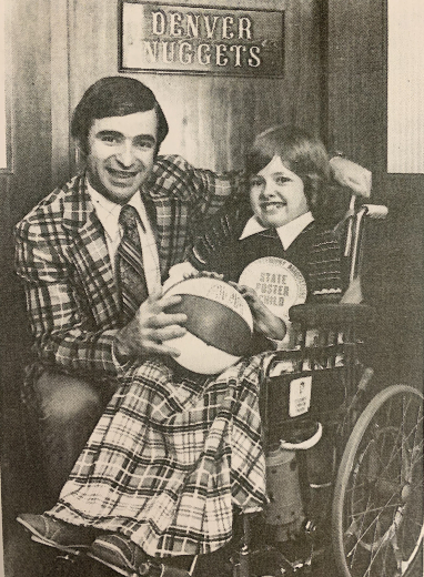 Laura holds a basketball in front of a sign that says Denver Nuggets
