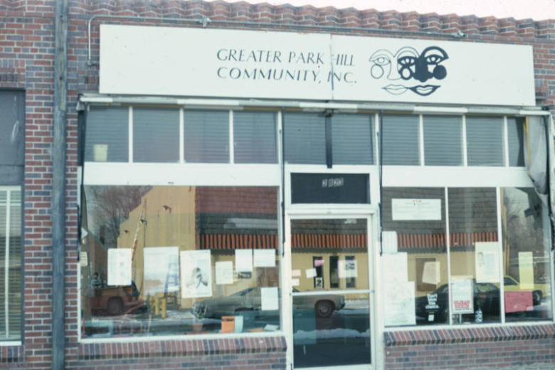 View of the non-profit Greater Park Hill Community, Inc. at 2823 Fairfax Street in the North Park Hill neighborhood of Denver, Colorado.  The one story brick commercial style building has a decorative dogtooth course. The structure has large front windows with clear transoms.  Above the transom is a sign that reads: "Greater Park Hill Community, Inc."
