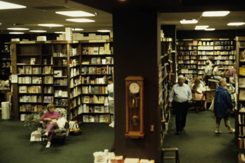 View of the interior of the Tattered Cover Bookstore at 2955 East 1st (First) Avenue in the Cherry Creek Neighborhood of Denver, Colorado. Shows bookshelves, customers and staff. A case clock is on a square column and a woman reads in an overstuffed chair.