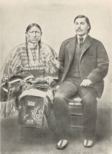 Portrait of George Bent, a mixed-blood who chose to live and fight as a Cheyenne warrior, with his wife Magpie. Bent wears a suit and moccasins, he has a moustache. Magpie wears a dress decorated with elk teeth, quillwork and fringe, and a hairpipe choker; her hair is in braids.