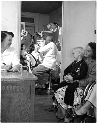 Dr. Clarence Holmes with Patient in Operating Room with Assistant Lucia Burrell at Desk