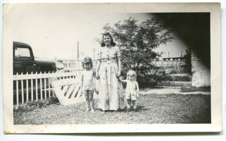 Photograph of a woman and two small children holding hands in the front yard of the Wonder home in Globeville, Colorado.  Sections of this neighborhood were demolished to make way for Interstate 70.