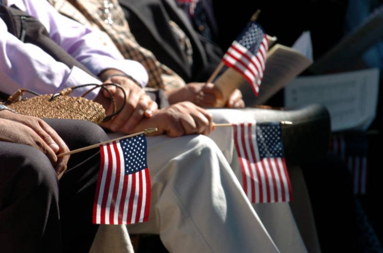 Several people sit holding small American flags in their hands