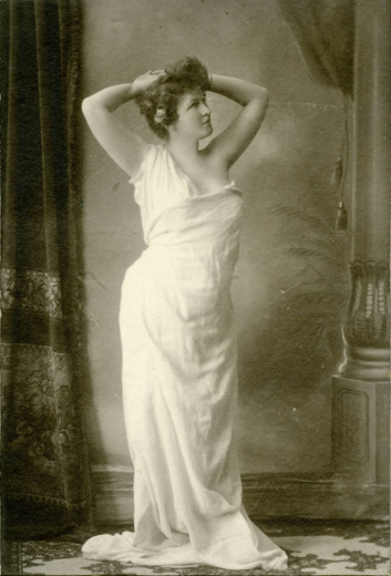 Studio photograph of Polly Pry in a classical pose wearing a diaphonous drapery.