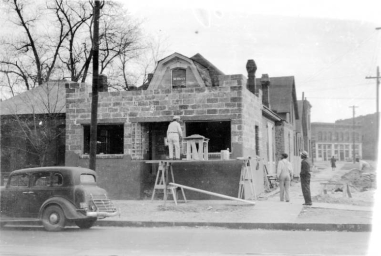Construction workers work on a brick extension to a house at 2602 Welton Street in the Five Points neighborhood of Denver, Colorado. An automobile is parked nearby. The building will be used as Clarence F. Holmes' dental office.
