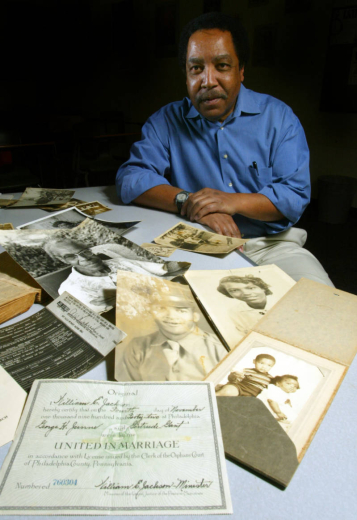 A man sits at a table that is covered with family documents