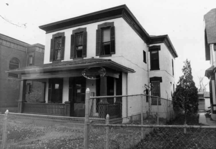View of a house at 2915 Champa Street in the Five Points (Curtis Park) neighborhood of Denver, Colorado. The two-story brick house has a covered porch, decorative shutters, and window trim.