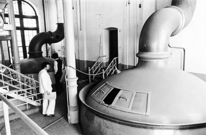 Interior view of the abandoned Tivoli-Union Brewery in Denver, Colorado; shows beer vats, stair railings, and men.
