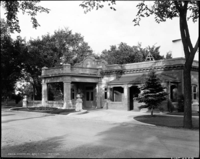 View of Riverside Cemetery in Denver, Colorado; shows a brick building with a porte cochere, balustrades, urns, and landscaping.