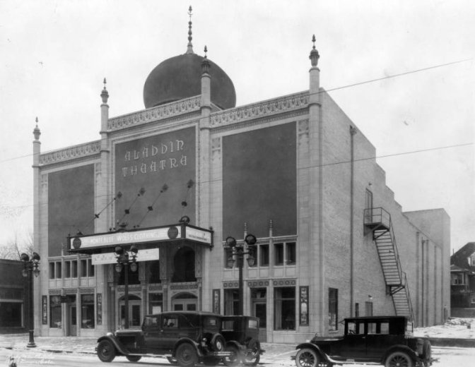 View of the Aladdin Theatre (with Moorish arches and onion dome) at 2010 Colfax Street, in Denver, Colorado;  also shows streetlamps and cars. Marquee reads: "Monte Blue - Wolf's Clothing."