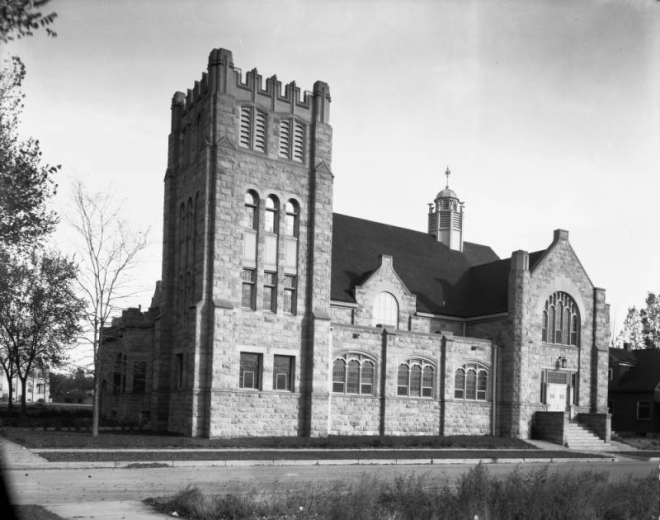 View of the Montview Boulevard Presbyterian Church at 1980 Dahlia Street in the South Park Hill neighborhood of Denver, Colorado. The stone church has a tower with battlements, arched windows, and stained glass windows decorated with tracery.