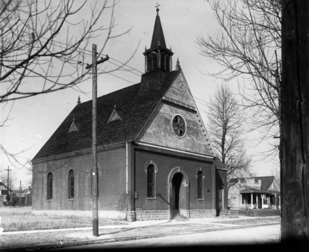 View of the North Denver Seventh-Day Adventist Church at 3925 Shoshone Street in the Sunnyside neighborhood of Denver, Colorado. The brick and stone church has arched windows, a circular stained glass window, and a steeple with a cross.