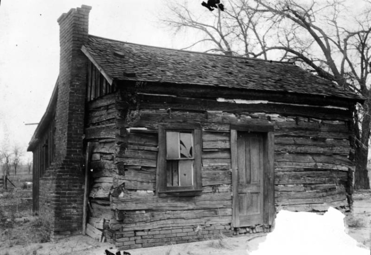 View of the William Hanford "Uncle Billy" Clark house at 5041 Pearl Street in the Globeville neighborhood of Denver, Colorado. The wood cabin has a brick chimney and pitched roof.