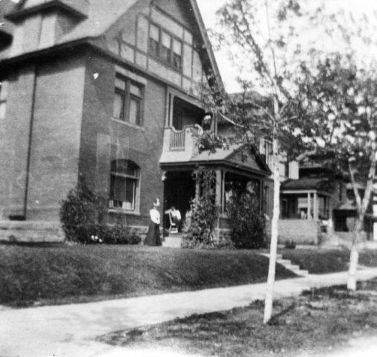 View of the Frank Hall residence at 1321 Columbine Street in the Congress Park neighborhood of Denver, Colorado; features half timbering. Women stand on the covered porch.