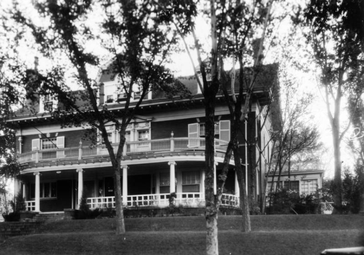 View of the Sidney W. Sinsheimer house at 738 Pearl Street in the Capitol Hill neighborhood of Denver, Colorado. The two-story house has dormers, a balcony, a covered porch with columns, and a one-story extension.