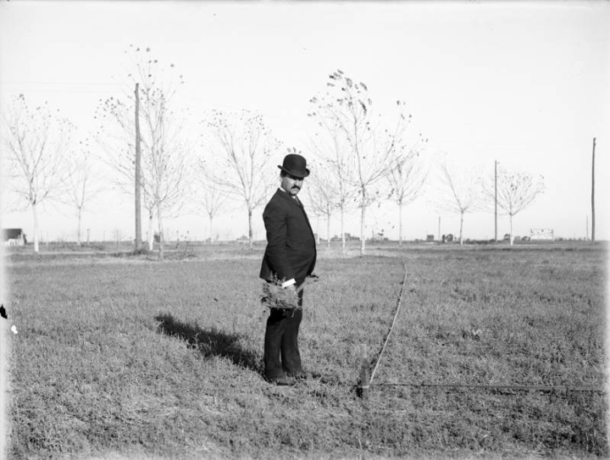 Senator and real estate developer Elmer W. Merritt holds a shovel full of dirt at a ground breaking ceremony in Denver, Colorado. Sign in background reads: "Park Hill, This Property Will Be Sold On Easy Terms With Building Restrictions, Modern Houses For Sale."
