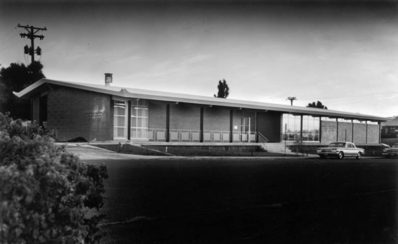 Ross-University Hills Branch of the Denver Public Library at 4310 East Amherst Avenue at South Birch Street in Denver, Colorado, is a wide, low, brick building with a slightly sloping roof. A Corvair sedan is parked.