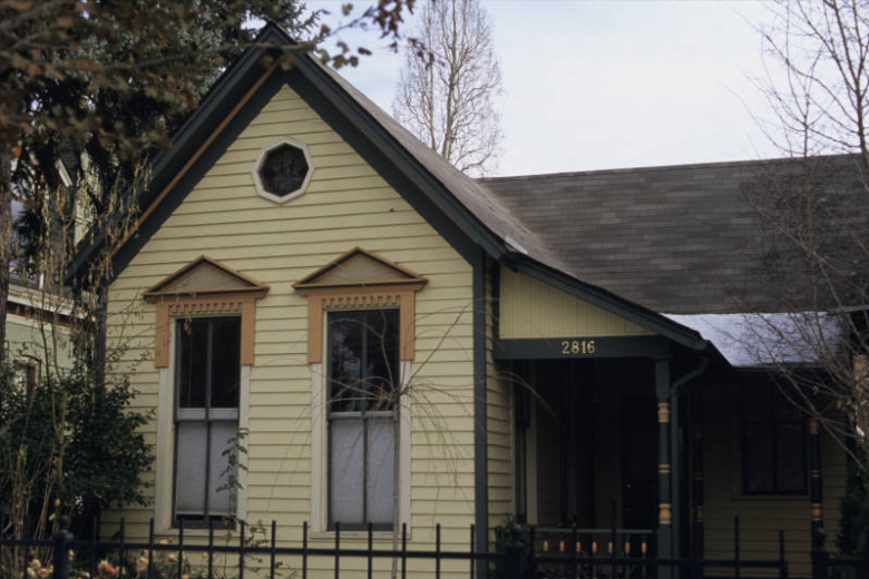 View of 2816 Curtis Street (ca. 1880) in the Five Points (Curtis Park) neighborhood of Denver, Colorado. The wooden one-story vernacular cottage has a cross-gabled roof and a small porch at the side. The residence is listed on the National Register of Historic Places as a contributing resource to the Curtis Park-Champa Street Historic District.