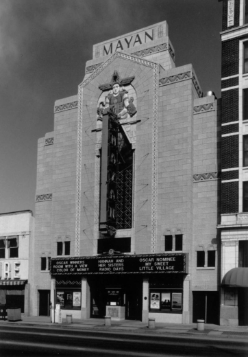 View of the Art Deco style Mayan Theater (Montana S. Fallis, architect, 1930) at 110 Broadway Street in the Speer Neighborhood of Denver, Colorado. The four story building is stone clad with Pre-Columbian motifs and a bas relief of a ritual officiate in multi-color terra cotta ornament by Julius P. Ambrusch of the Denver Terra Cotta Company. The marquee reads: "Oscar Winners, Room With A View, Color of Money, Hannah and Her Sisters, Radio Days, My Sweet Little Village."