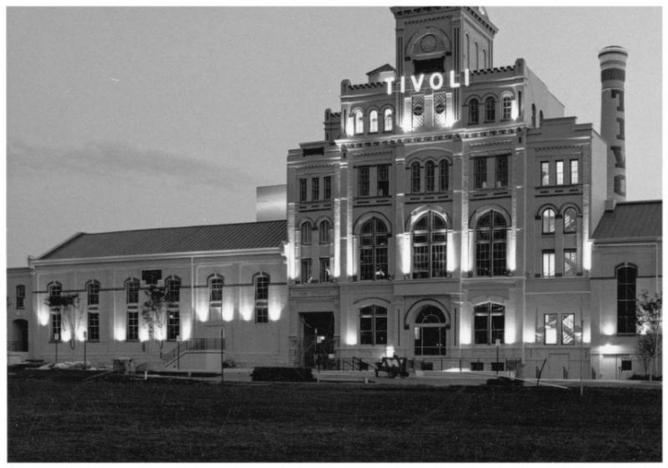 Night view of the Tivoli Brewery Building (formerlyTivoli-Union Brewery) at 10th (Tenth) and Larimer Streets in the Auraria neighborhood of Denver, Colorado. The four-story brick building has arched windows, a smokestack, and a tower with a mansard roof. A sign reads: "Tivoli Beer."