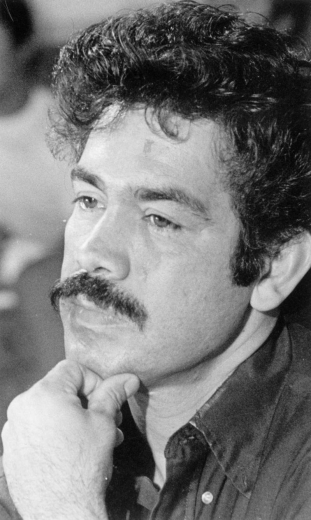 Portrait of Rodolpho "Corky" Gonzales, political activist and founder of the Crusade for Justice. Mr. Gonzales has a moustache and curly hair, and he rests his chin on his hand.