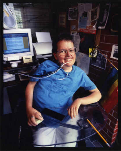 Portrait of Laura Hershey seated by her desk. Photographer unknown.