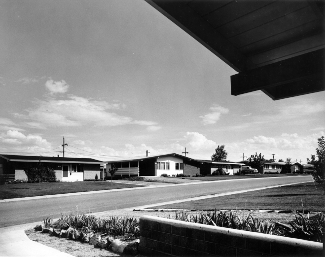 View of homes in the Harvey Park Addition of Denver, Colorado; shows California bungalow style residences with carports, lawns, and flower beds of iris. These houses were built by Carey Construction and advertised as "Holiday Homes."
