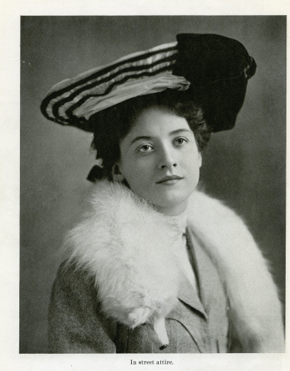 Portrait of Maude in street attire, a mink fur wraps around her