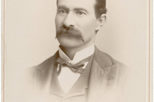 Studio portrait of Colorado State Senator (Las Animas County) Casimiro Barela. He wears a vest and jacket, a bow tie and an upright collar. He has a full, waxed mustache and his dark hair has a cowlick and is parted on the side.