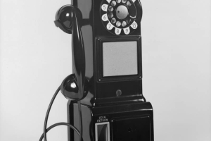 View of a pay telephone. The phone has a slot to deposit nickles, dimes, and quarters, a dial, and coin return.