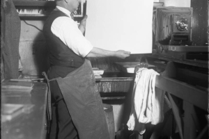 Interior view of Harry M. Rhoads in his dark room; also shows a bellows camera.