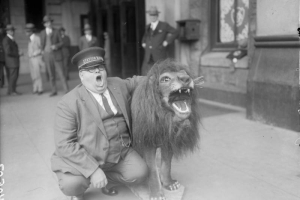 The station master at Union Station in Denver, Colorado stretches his mouth open in a "roar" to mock a fur covered statue of a roaring lion.