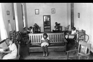 Native American Ute girls pose at wooden desks and a sofa reading books inside their dorm, Southern Ute Agency school, Ignacio, La Plata County, Colorado.