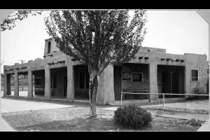 View of the Denver Municipal Trap Club clubhouse at Sloans Lake Park in Denver, Colorado. The adobe style building has wooden vigas and a sign that reads: "Denver Municipal Traps".