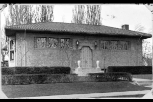 An exterior view of the Park Hill Branch Library located on Dexter and Montview Boulevard in Denver, Colorado. The Park Hill branch library building was built by architects M.R. & Burnham Hoyt and features spanish tiled roof, stucco exterior walls. Two vases are on either side of the brick steps.
