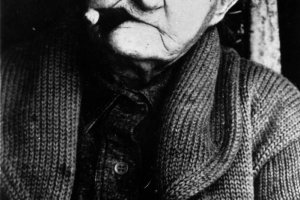 Studio portrait of Alice Ivers "Poker Alice" Tubbs. She smokes a cigar and wears a sweater.