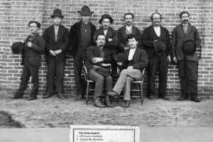Filemeno Gallotti, Leonardo Deodato, Michale Ballatti, Guiseppe Campigne, Frank Valendre "The Miner", Henry Ferandez, John Arrati, Leonardo Allesandre, and "The Ranchman", a group of criminals, pose outdoors in Denver, Colorado.
